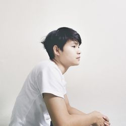 Portrait of young man looking away against white background