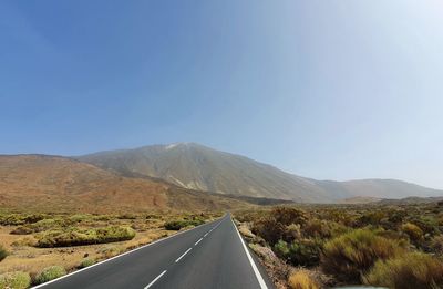 Road leading towards mountains against sky