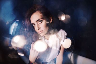 Portrait of young woman with defocused lights in darkroom