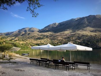 Man sitting on table by mountains against clear sky