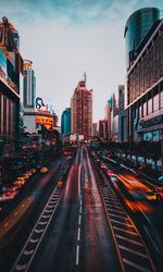Vehicles on road amidst buildings in city against sky
