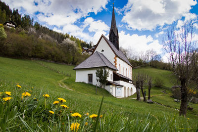 Scenic view of grassy field by houses against sky