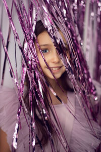 Beautiful girl with big eyes in a pink dress stands against the background of new year's tinsel