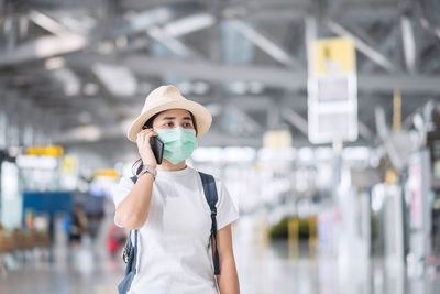 Woman with mask looking away in airport outdoors