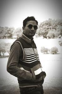 Portrait of young man standing by lake against clear sky