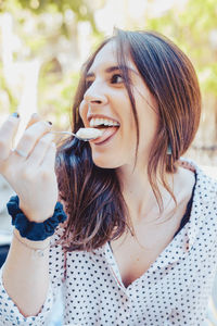 Young woman having ice cream while standing outdoors