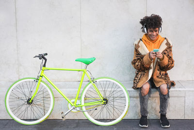 Full length of a young man with bicycle standing against wall