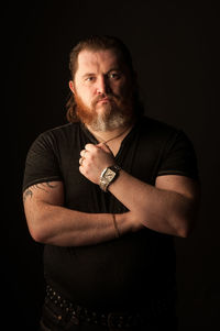 Portrait of man standing against black background