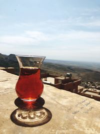 Close-up of beer glass on table against sky