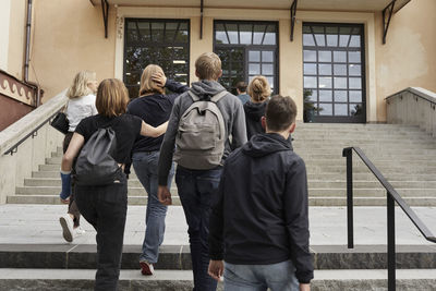 Rear view of teenagers in front of school