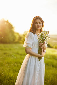 Portrait of young woman standing on field