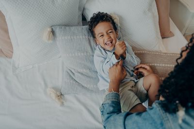 High angle view of happy boy lying on bed at home