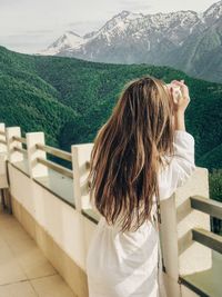 Rear view of woman standing on railing against mountains