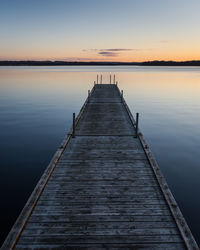 Pier over lake against sky during sunset