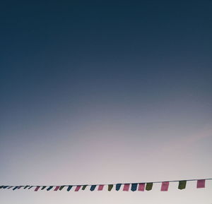 Low angle view of flags hanging against clear sky at dusk