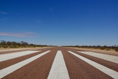 Road against clear blue sky