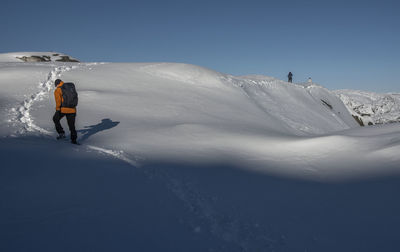 Rear view of man skiing on snowcapped mountain against sky