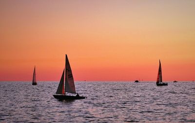 Sailboat sailing on sea against clear sky during sunset