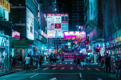 People walking on illuminated city street at night