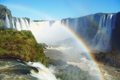 Scenic view of waterfall against rainbow in sky