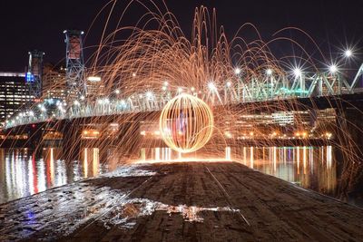 Fireball created with steel wool by illuminated hawthorne bridge at night