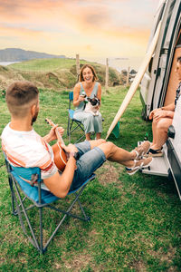 Friends with their dog drinking beer in front of their camper van