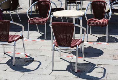 Empty chairs and tables at sidewalk cafe in city