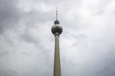 Low angle view of communications tower against cloudy sky