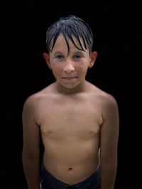 Portrait of shirtless boy against black background