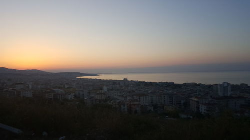 High angle view of townscape by sea against sky during sunset