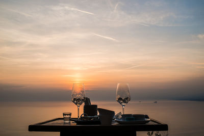 Close-up of beer on table against sea during sunset