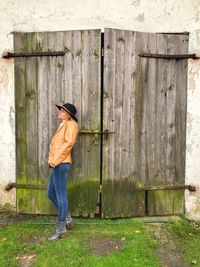 Full length of a woman standing against wooden door