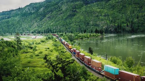 High angle view of freight train by lake against mountain