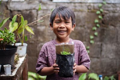 Portrait of young boy standing against plants