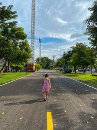 Rear view of woman on road against sky in city