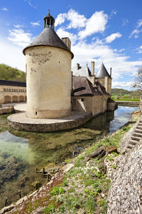 Old building by river against sky