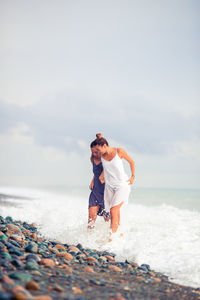 Men standing on beach against sky