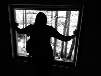 Silhouette man standing by window in darkroom