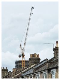 Crane by building against sky