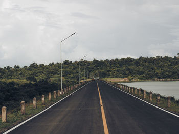 Road by trees against sky