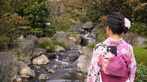 Rear view of woman in kimono looking at stream