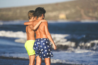 Rear view of shirtless man standing at beach