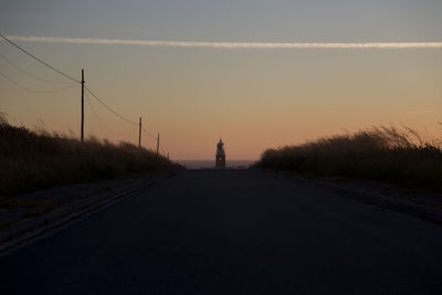 Silhouette man on road against sky at sunset