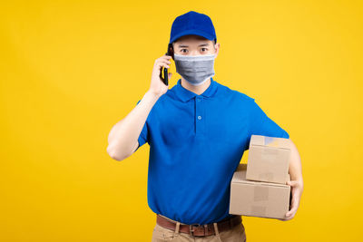 Portrait of young man standing against yellow background