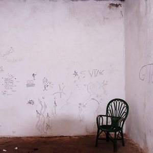 Empty chairs and table against wall