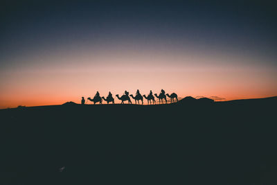 Silhouette people against clear sky during sunset