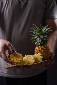 Midsection of man holding pineapple in plate