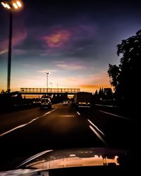 Cars on road against sky at sunset