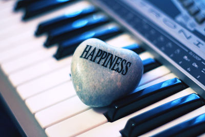 High angle view of happiness text on heart shape rock over piano key