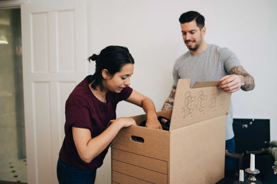 Man assisting woman in unpacking box at new house